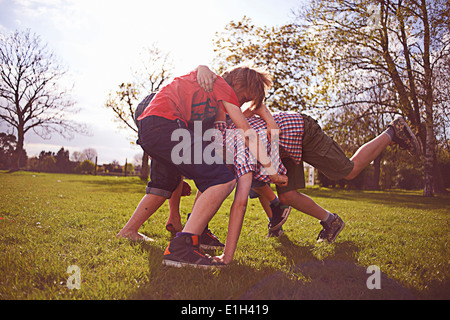 Boys play fighting on playing field Stock Photo