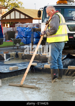 self building house, pouring floor slab, man roughly levelling concrete manually Stock Photo