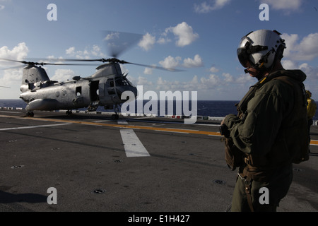 U.S. Marine Corps Staff Sgt. Caleb Thompson, a crew chief, watches a CH-46E Sea Knight helicopter with Marine Medium Helicopter Stock Photo