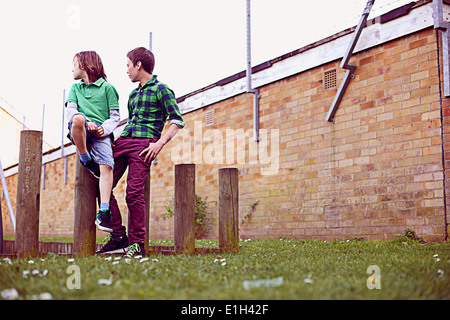 Two boys sitting on wooden poles Stock Photo