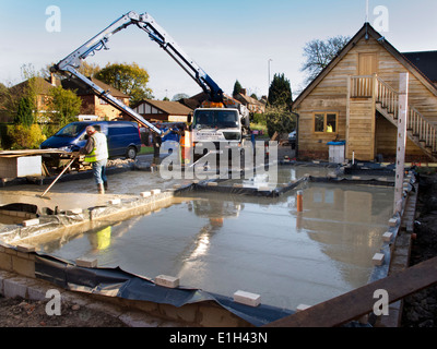 self building house, man tamping freshly poured concrete floor slab level Stock Photo