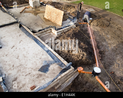 self building house, men setting out drains around house, Stock Photo