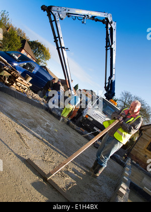 self building house, man tamping freshly poured concrete floor slab level Stock Photo