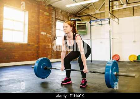 Woman lifting barbell in gym Stock Photo