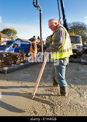 self building house, man tamping freshly poured concrete floor slab level Stock Photo