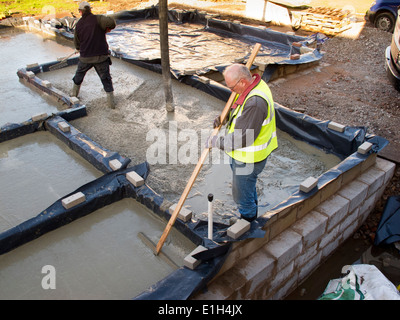 self building house, pouring floor slab, man levelling concrete by hand raking Stock Photo