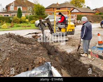 self building house, men excavating ditches for drains with mini digger excavator machine Stock Photo