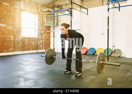 Woman lifting barbell in gym Stock Photo