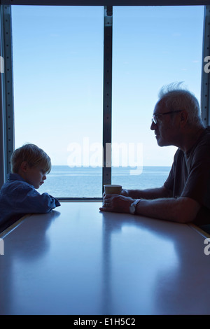 Young boy and father sitting at table on ferry