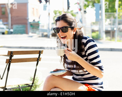 Young woman drinking coffee at sidewalk cafe Stock Photo