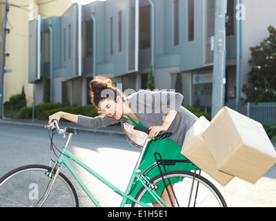 Young woman with bicycle and falling cardboard boxes Stock Photo