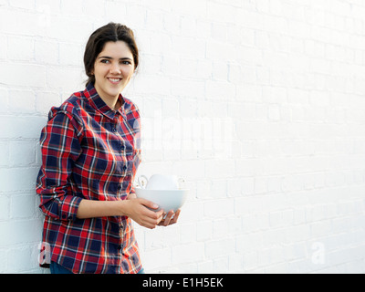 Portrait of smiling young woman holding crockery Stock Photo