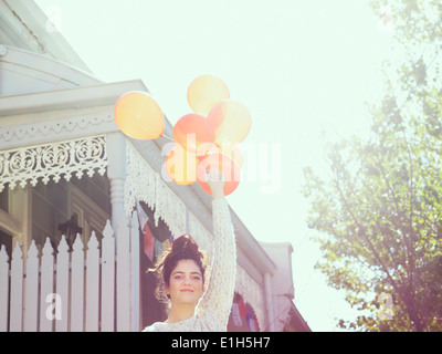 Portrait of young woman holding up a bunch of balloons Stock Photo