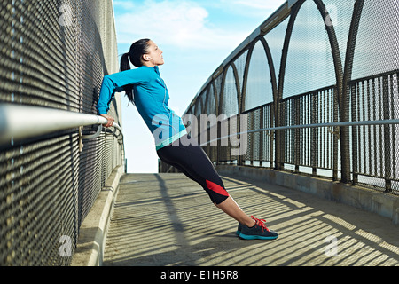 Mid adult woman stretching on bridge Stock Photo