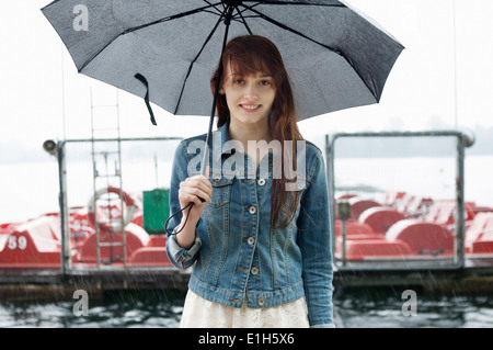 Portrait of young woman by lake with umbrella Stock Photo