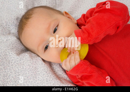 7 month old baby girl in crib with teething ring in her mouth Stock Photo