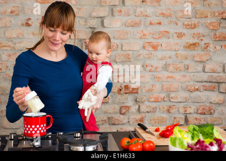 Mother carrying baby daughter whilst preparing lunch