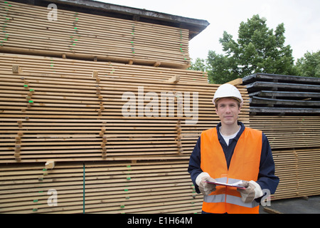 Portrait of young male worker with clipboard in timber yard Stock Photo