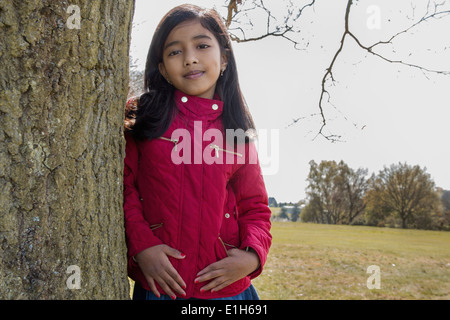 Portrait of girl leaning against tree trunk Stock Photo