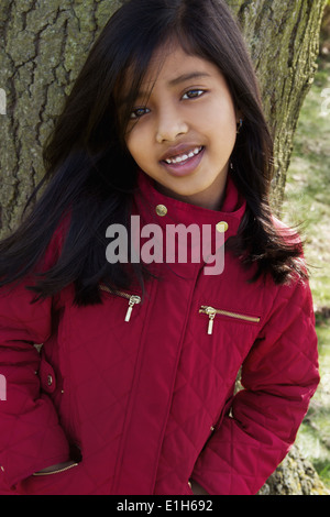 Close up portrait of girl leaning against tree trunk Stock Photo