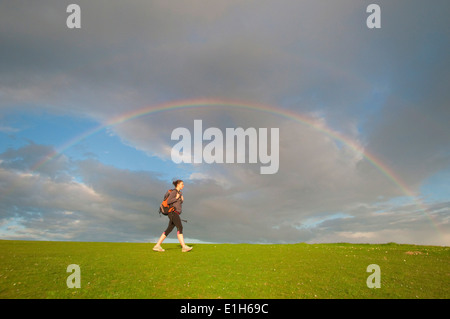 Young female hiker, hiking below rainbow Stock Photo