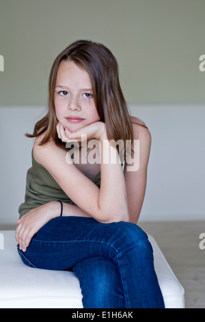 Portrait of sullen twelve year old girl with hand on chin Stock Photo