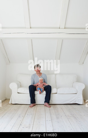 Portrait of mature father with baby daughter on sofa Stock Photo