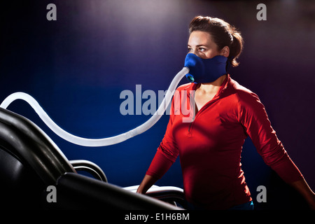 Mid adult woman with face mask on gym treadmill in altitude centre Stock Photo