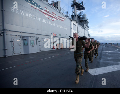PACIFIC OCEAN - Rifleman Lance Cpl. Matthew Stowe runs with an M240B medium machine gun aboard USS Makin Island here Dec. 7. St Stock Photo