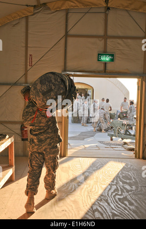 A U.S. Soldier carries a duffle bag out to the loading area prior to it being searched during a mini-getaway at Camp Virginia, Stock Photo