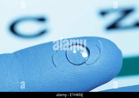 Intraocular lens on gloved finger. Intraocular lens is an artificial lens surgically implanted in the human eye. Stock Photo
