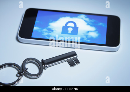 Secure smart phone. A key next to smartphone with a lock over a cloud on its screen. Stock Photo