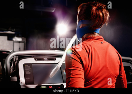 Mid adult female with face mask running on gym treadmill in altitude centre Stock Photo
