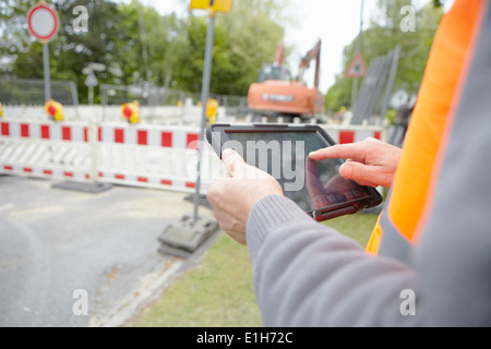 Close up of foremans hands using digital tablet on road construction site Stock Photo