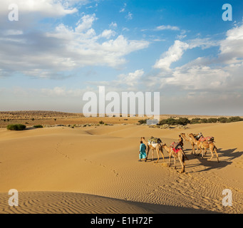 Two cameleers (camel drivers) with camels in dunes of Thar desert Stock Photo