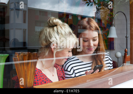 Young women through window, looking at smartphone Stock Photo