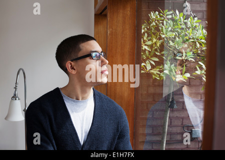 Young man looking through window Stock Photo