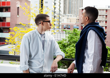 Young men standing on balcony in London, UK Stock Photo