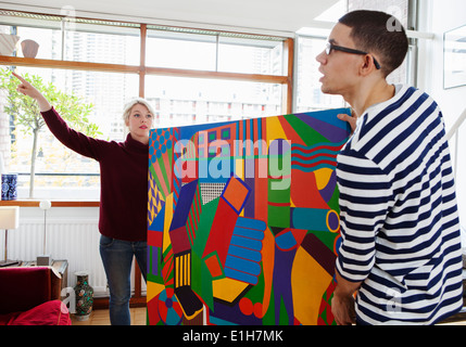Young couple putting up painting in living room Stock Photo