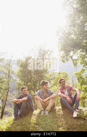 Three young men sitting on grass Stock Photo