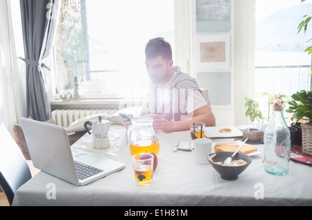 Young man having breakfast and using laptop Stock Photo
