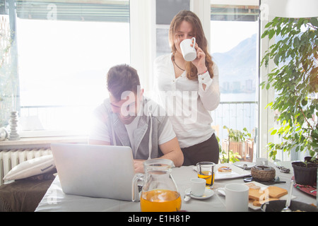 Young man having breakfast and using laptop Stock Photo