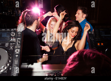 Group of friends dancing in front of DJ in nightclub Stock Photo