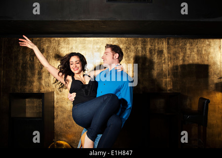 Young man dancing and carrying young woman in nightclub Stock Photo
