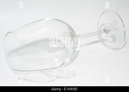 Shattered broken-down wine glass with sharp shards lying on white background Stock Photo