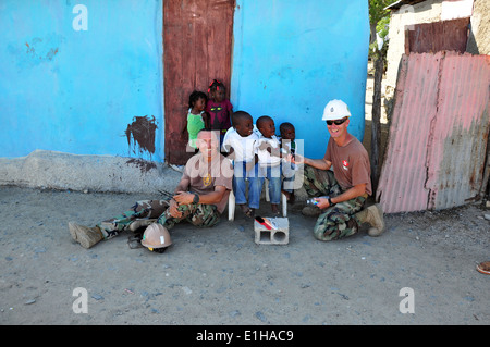 U.S. Sailors assigned to Naval Construction Mobile Battalion (NCMB) 23 pose for a photograph with Haitian children during High Stock Photo