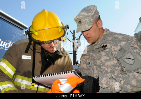 U.S. Army Staff Sgt. Michael Dement, right, assigned to the 301st Chemical Company, Kentucky National Guard, talks with a firef Stock Photo