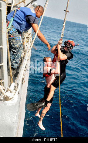 U.S. Navy Boatswain’s Mate 2nd Class Steven Wagner, upper right, a search and rescue swimmer assigned to the guided missile d Stock Photo