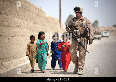 U.S. Marine Corps Lance Cpl. Jacob Kartchner, assigned to 3rd Battalion, 3rd Marine Regiment, walks with Afghan children during Stock Photo