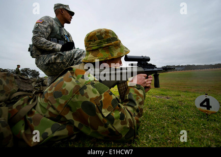 Australian Army Pvt. Luke Challman fires at 300-meter targets while U.S. Army Sgt. Marcus Fontenot, with the 2nd Brigade , 25th Stock Photo